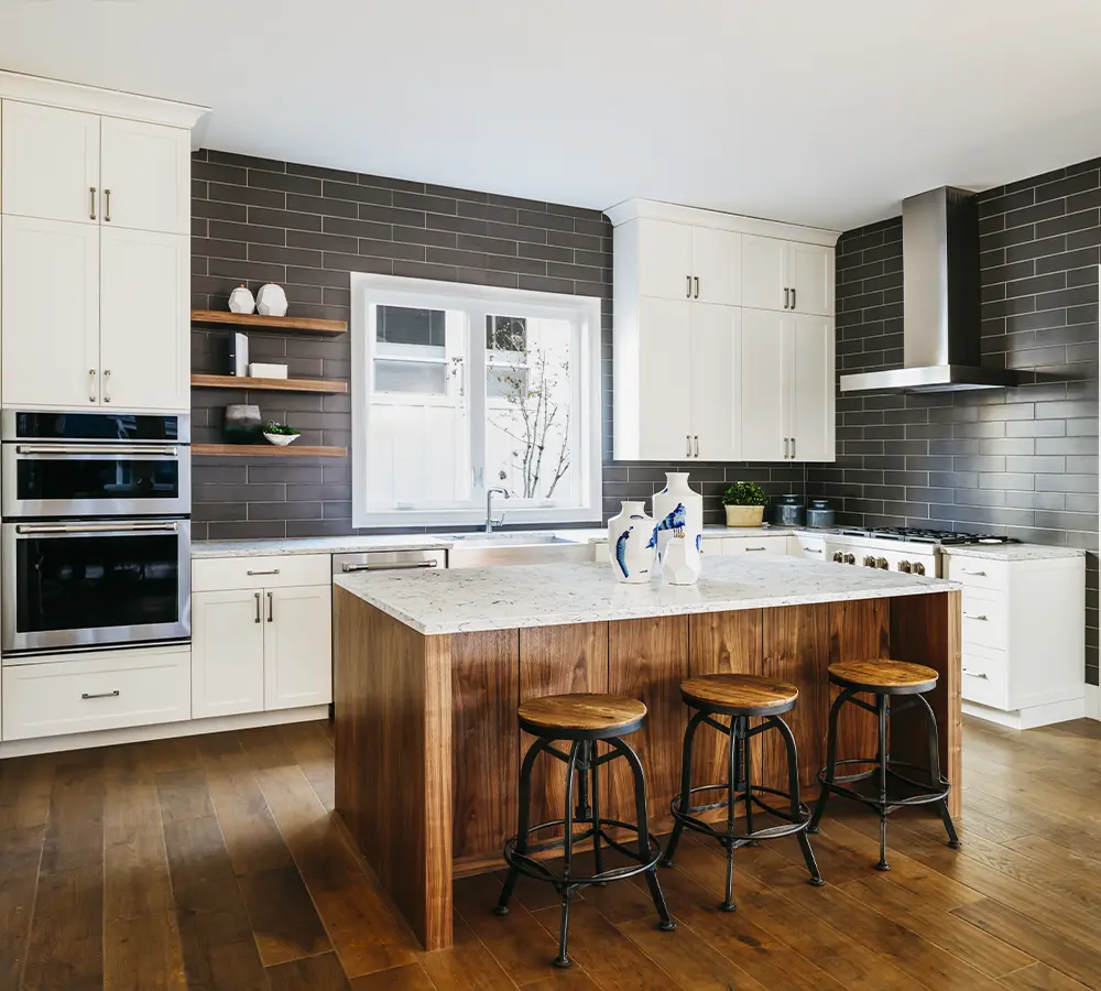 Contemporary kitchen with a large wood and marble island, open shelving, and a gray brick backsplash.