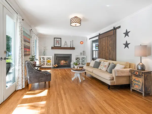 Modern farmhouse-style living room with barn door and cozy fireplace.