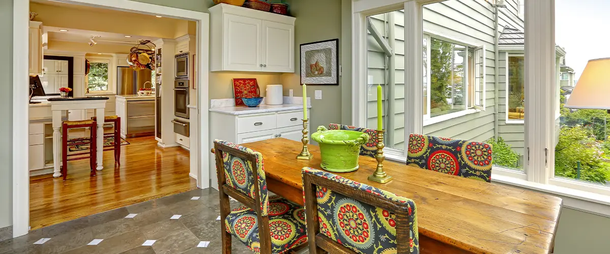 Bright home addition with skylight ceiling and rustic dining table connecting to open kitchen with white cabinetry