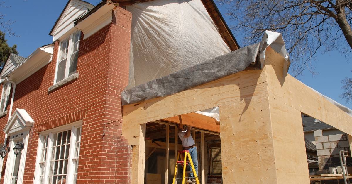 Framed garage addition in progress on brick house exterior