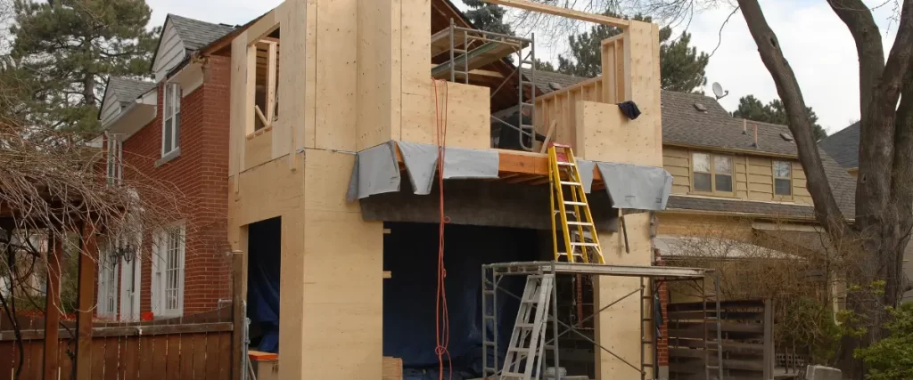 Second-story home addition under construction with scaffolding and ladders